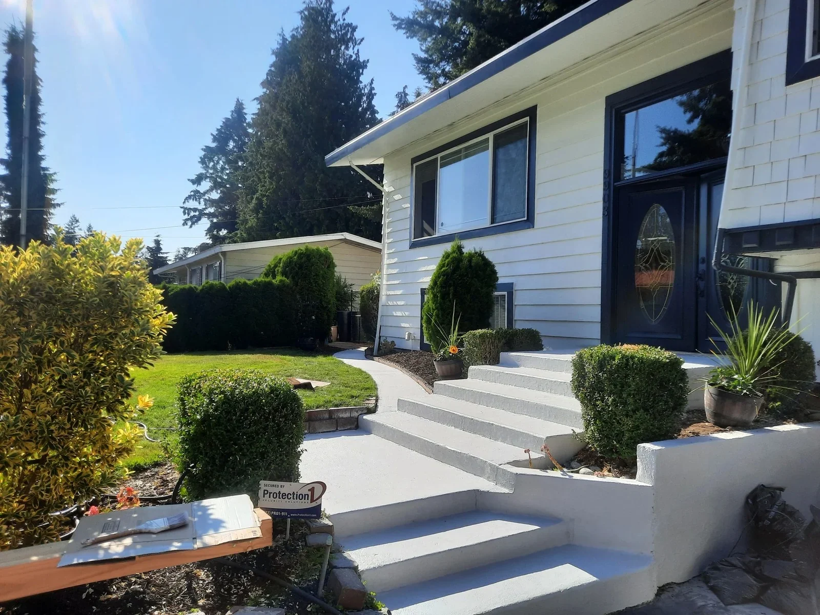 A white painted home with dark trim, front steps and established planting in LLN’s gallery