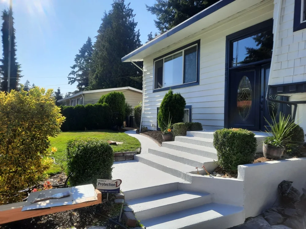 A white painted home with dark trim, front steps and established planting in LLN’s gallery
