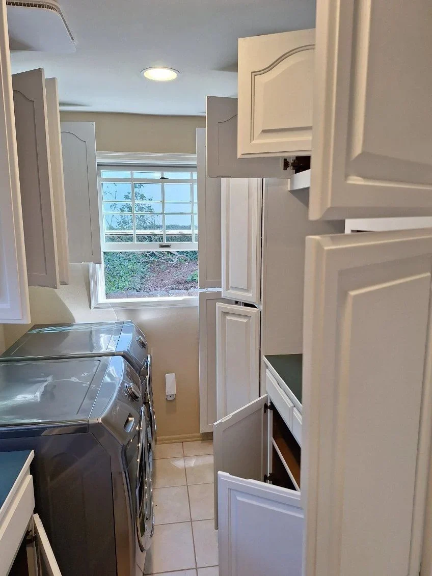 White cabinet doors and silver handles beside laundry appliances in LLN’s published gallery
